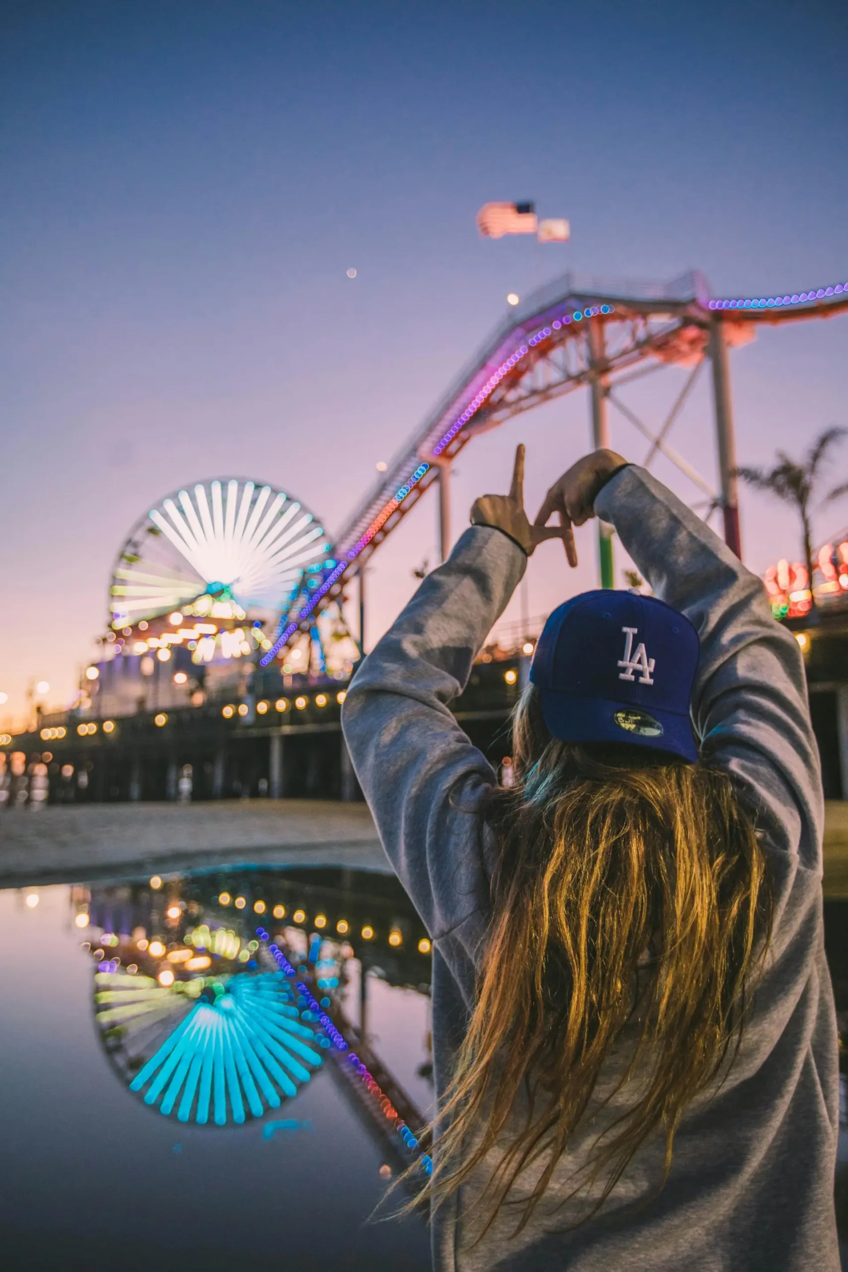 jeune femme formant le signe LA avec ses doigts devant le parc d'attractions de Santa Monica en Californie